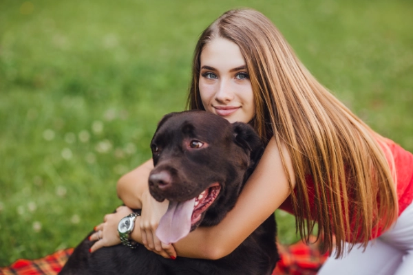 young beautiful girl hugs her dog garden